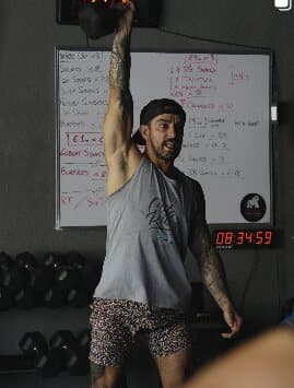 Athlete pressing a dumbbell overhead during class